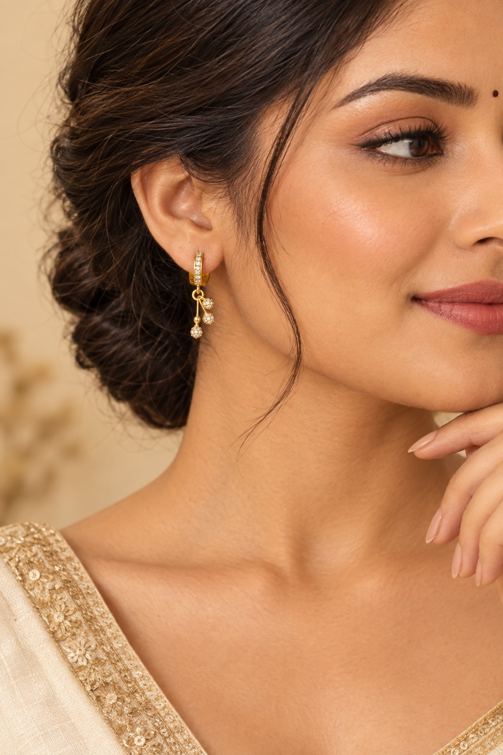 Gold plated drop earrings on model warm beige background