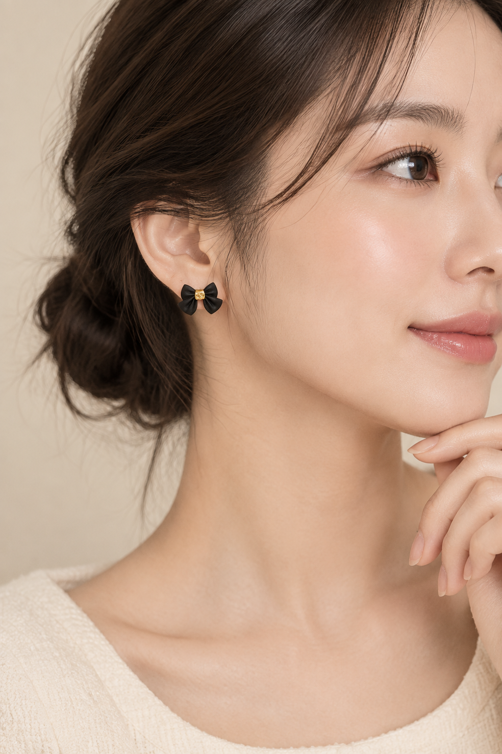 Black bow earrings on model beige background